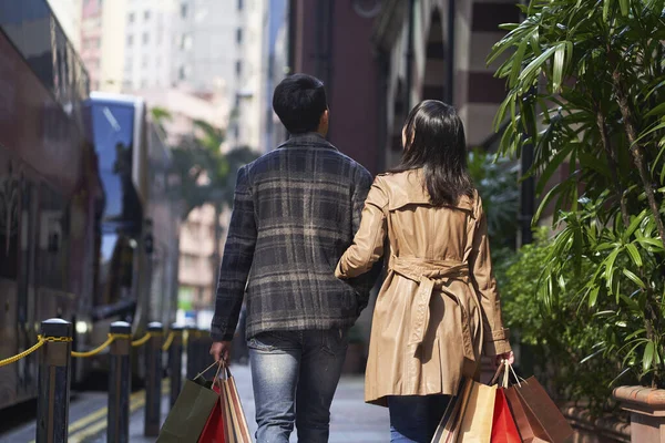 若いアジア人のカップルが買い物袋を手に街を歩く姿を — ストック写真