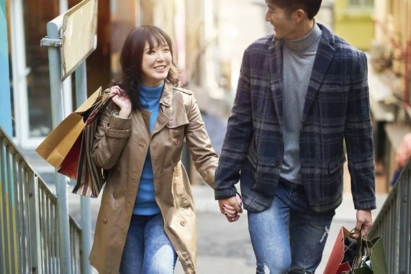 happy young asian couple walking talking holding hands while shopping in the city
