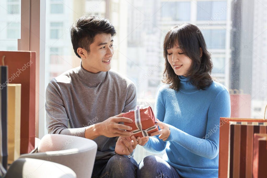 asian man giving young woman girlfriend a christmas or birthday gift
