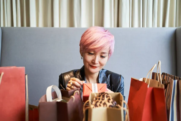 若いアジアの女性がソファに座ってクリスマスプレゼントの箱を開く — ストック写真