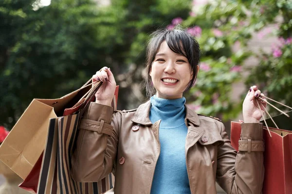 カメラを見て笑顔で買い物袋を持って美しい幸せな若いアジア人 — ストック写真