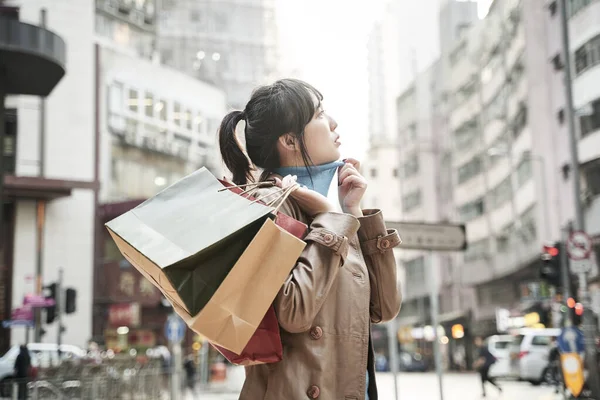 街を歩いて買い物袋を持った若いアジア人女性が — ストック写真