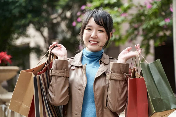 カメラを見て笑顔で買い物袋を持って美しい幸せな若いアジア人 — ストック写真