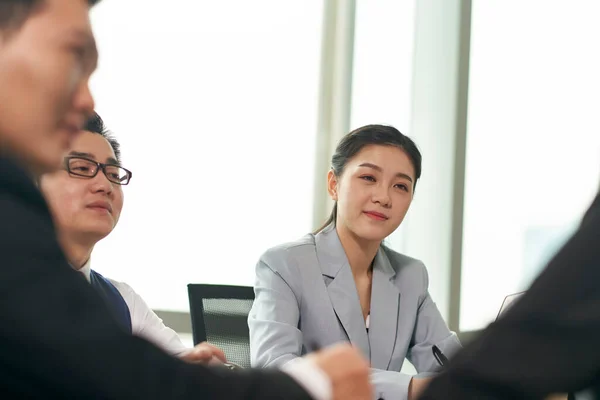 年轻的亚洲女商人在办公室开会时倾听同事们的谈话 — 图库照片