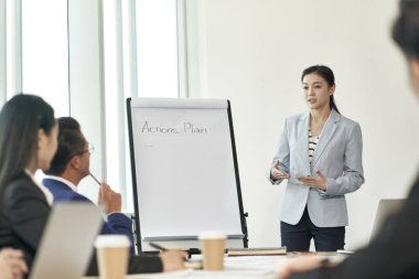 young asian business woman facilitating a discussion during team meeting in office clipart