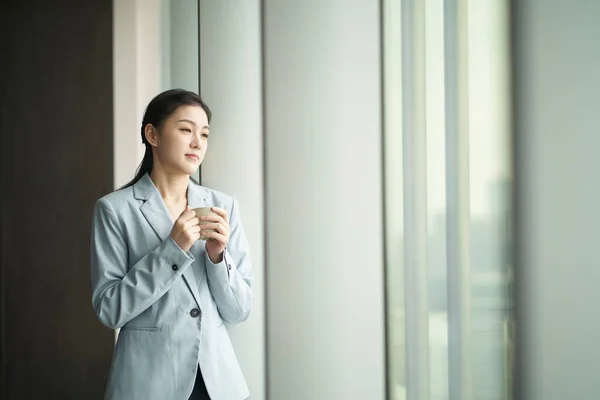 Junge Asiatische Geschäftsfrau Steht Fenster Und Hält Eine Tasse Kaffee — Stockfoto