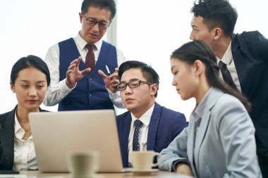 Asyalı şirket yöneticileri dizüstü bilgisayarla iş görüşmesi yapıyorlar.