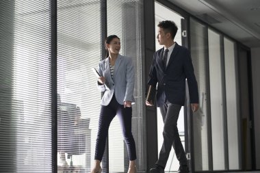 İki Asyalı iş adamı ofiste yürürken konuşmaya gidiyorlar.