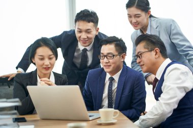 Asyalı şirket yöneticileri dizüstü bilgisayarla iş görüşmesi yapıyorlar.