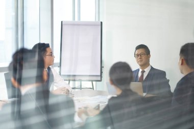 Asyalı şirket yöneticileri konferans odasında toplanıyor.