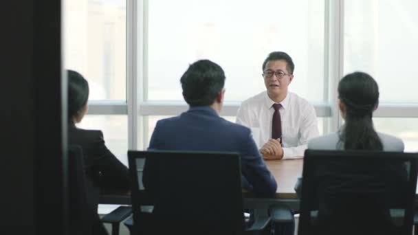 現代企業のオフィスで人事担当者のグループにインタビューされている神経成熟したアジアのビジネスマン — ストック動画