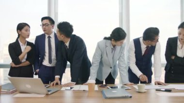 Asyalı iş adamlarından oluşan bir ekip şirket konferans salonunda iş planını tartışıyor.