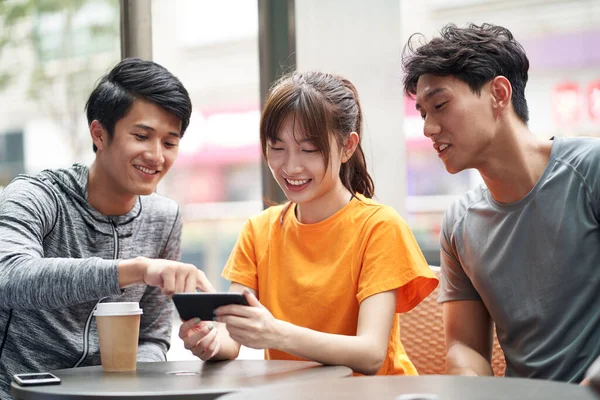 三个年轻的亚洲成年人一起坐在户外咖啡店里用手机 — 图库照片