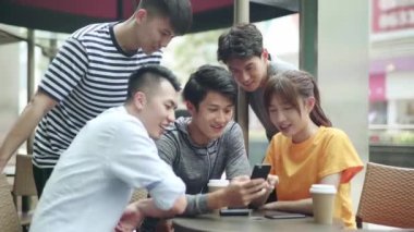 Sosyal medya mesajlarına cep telefonuyla bakan beş genç Asyalı yetişkin.