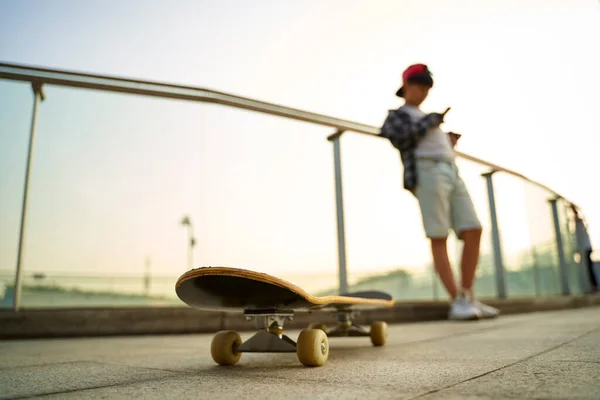 Adolescente Asiático Skatista Menino Olhando Para Telefone Móvel Enquanto Descansa — Fotografia de Stock