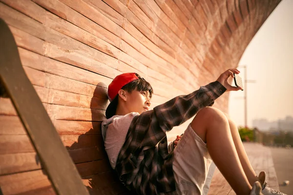 十代のアジアのスケートボーダー少年は携帯電話を使って自画撮り — ストック写真