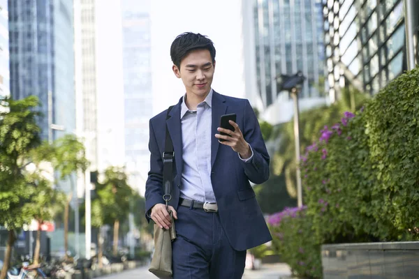 Joven Asiático Hombre Negocios Mirando Mensajes Celular Mientras Caminando Calle —  Fotos de Stock