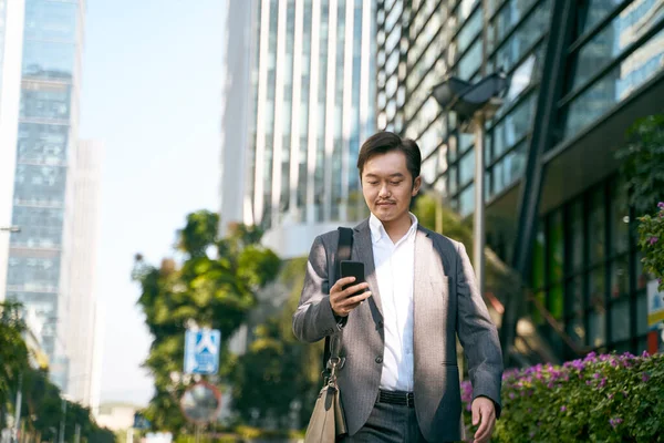 Asijský Podnikatel Při Pohledu Mobilní Telefon Při Chůzi Práce Cbd — Stock fotografie