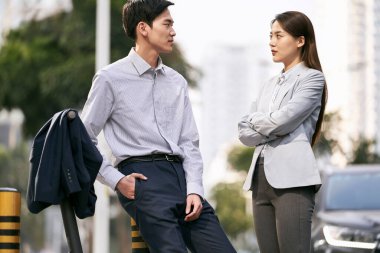 İki Asyalı iş adamı modern şehrin merkezinde sokakta sohbet ediyorlar.