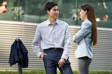 İki genç Asyalı iş adamı sokakta dikilip sohbet ediyorlar.