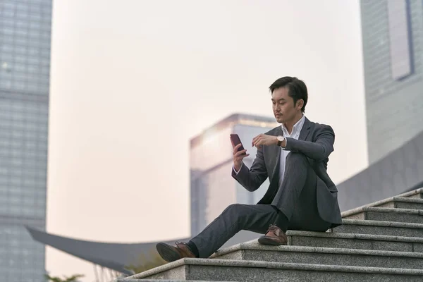 Asiatischer Konzernchef Sitzt Auf Stufen Und Schaut Aufs Handy — Stockfoto