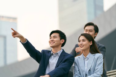 Üç Asyalı şirket yöneticisinden oluşan bir ekip dışarıda sohbet ediyor.