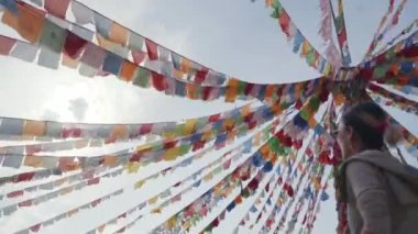 Tibet dua bayrakları arasında yürüyen Asyalı kadın turist