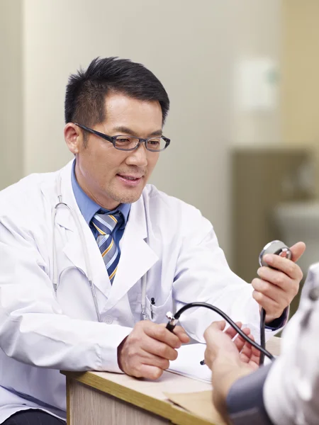 Doctor measuring blood pressure — Stock Photo, Image