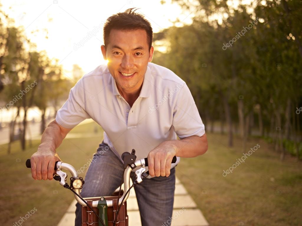 asian man riding bike outdoors at sunset