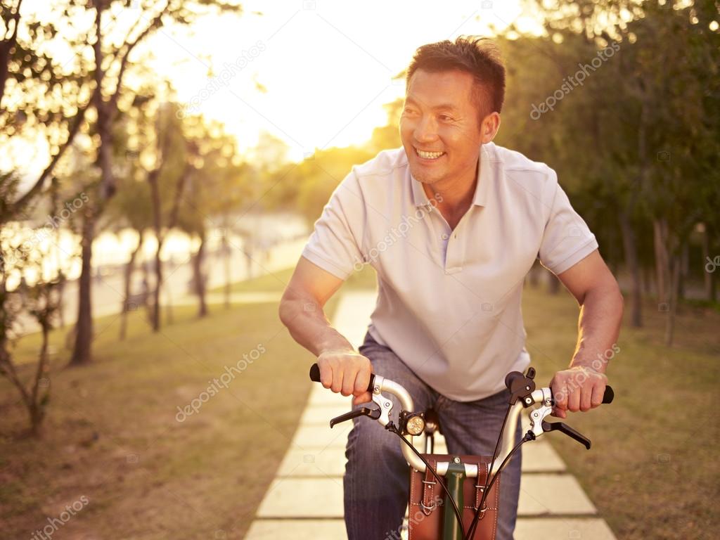 asian man riding bike outdoors at sunset