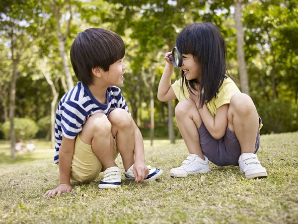 Asiatische Kinder spielen mit Lupe im Freien — Stockfoto