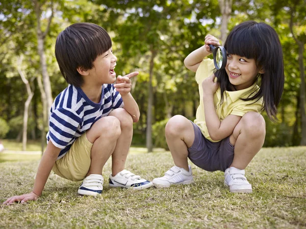 Niños asiáticos jugando con lupa al aire libre — Foto de Stock