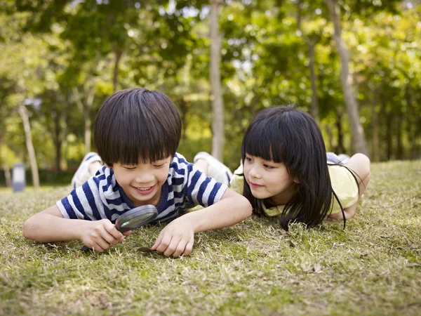 Aziatische kinderen spelen met Vergrootglas buitenshuis — Stockfoto