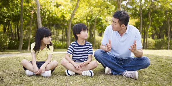 Asiatique père et les enfants parler dans parc — Photo