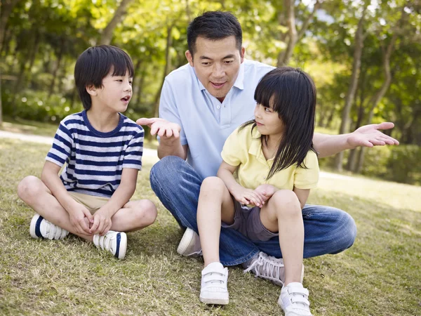 Азиатский отец и дети разговаривают в парке — стоковое фото