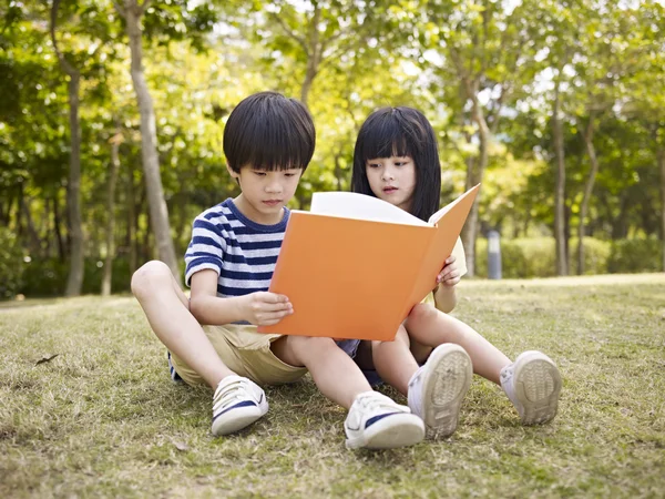 Azjatyckie dzieci czytanie książki na zewnątrz — Zdjęcie stockowe