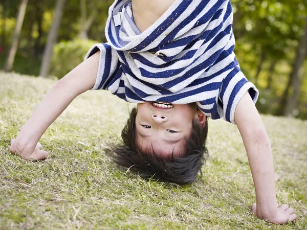 Asian child standing on hands outdoors — Stock Photo, Image