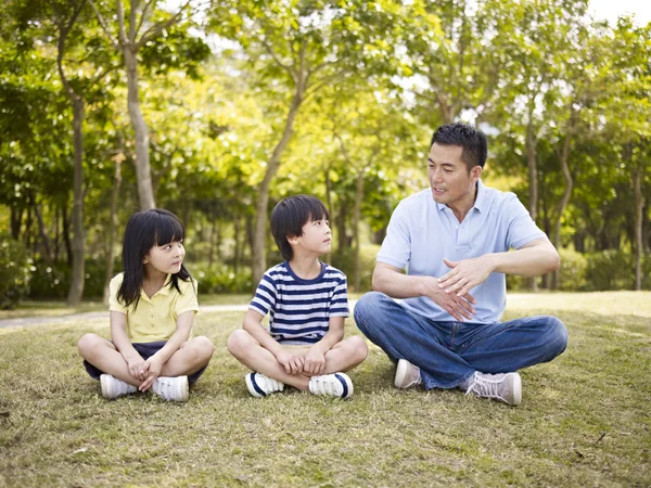 Asiático pai e crianças falando no parque — Fotografia de Stock