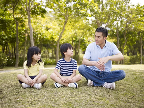 Asiatique père et les enfants parler dans parc — Photo