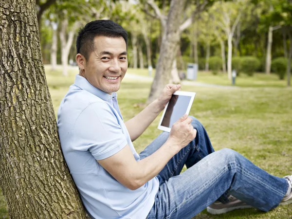 Азиатский человек с помощью планшета на открытом воздухе — стоковое фото