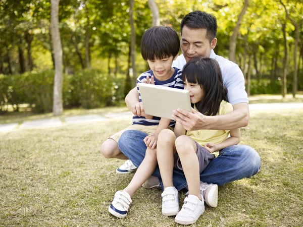 Asya baba ve çocuk kullanarak açık havada tablet — Stok fotoğraf