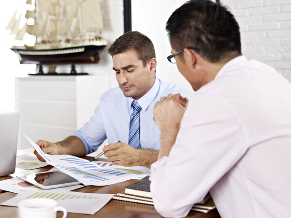 Multinational businesspeople discussing sales performance in office