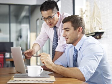 asian and caucasian businessmen working together in office clipart