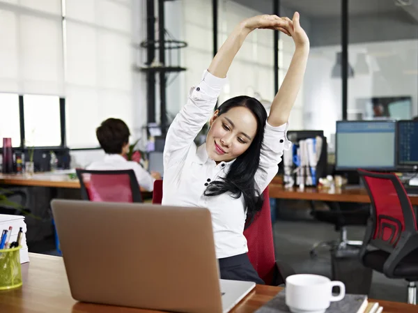 Asiático mujer de negocios estirando brazos en oficina — Foto de Stock