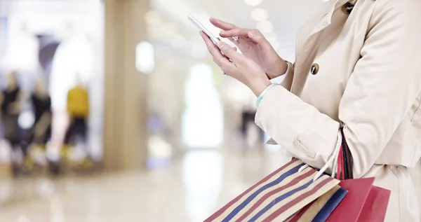 Mujer usando el teléfono celular mientras va de compras — Foto de Stock