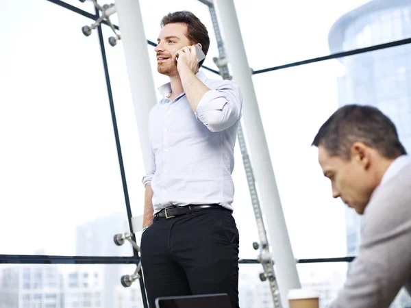 Uomo d'affari che parla al cellulare in ufficio — Foto Stock