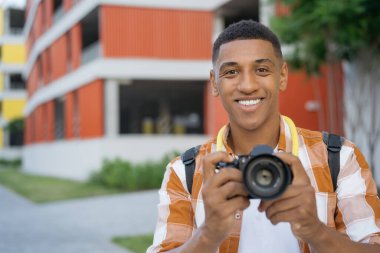 Profesyonel Afro-Amerikan fotoğrafçı portresi. Sokakta kameraya bakarak fotoğraf çekiyor. Dışarıda dijital kamera tutan bir turist, kopyalama alanı. Seyahat kavramı