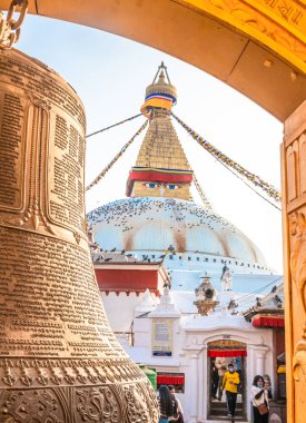 Katmandu, Nepal - 29 Ocak 2021: Budist el yazmaları altın çan üzerine yazılmış ve arka planda Boudhanath Stupa.