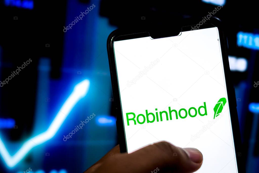 Kathmandu, Nepal - February 10 2021: Man holds smartphone with Robinhood application logo against the stock market chart in the background.