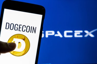 Katmandu, Nepal - 11 Mayıs 2021: Dogecoin logosu arka planda SpaceX logosu ile akıllı telefon üzerinde. SpaceX, Dogecoin 'i DOGE-1' in gelecek yıl Ay 'a fırlatılması için ödeme olarak kabul etti..